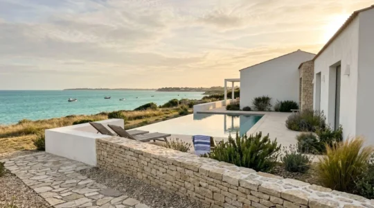 Contemporary white luxury villa with infinity pool overlooking turquoise coastal waters and natural Mediterranean landscape at golden hour